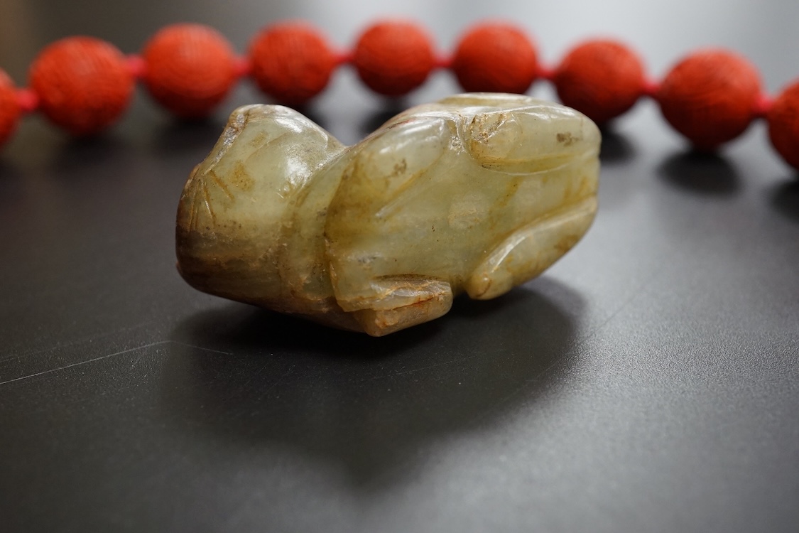 A Chinese red lacquered bead necklace and a bowenite jade figure of a cat